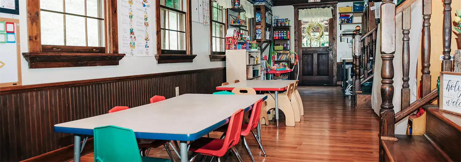 Inside a Small Miracles Daycare classroom with child-sized tables and chairs.