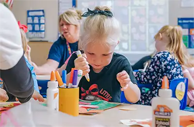 A child focused on an arts and crafts project at a classroom table