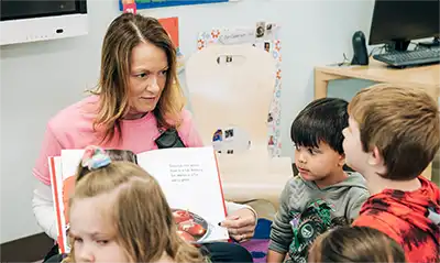 A teacher reading a picture book to a group of preschoolers